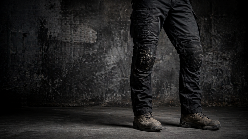 Black slim fit work trousers and boots against a dark concrete wall